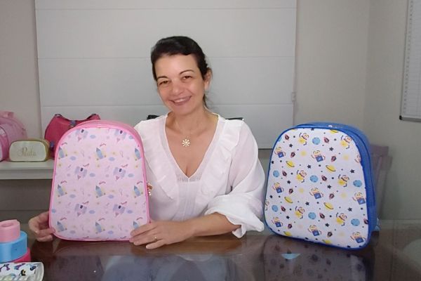 a criadora do molde Paula Lovato com duas mochilas, uma rosa e outra azul que utilizaram o molde de Mochila Escolar 
fácil